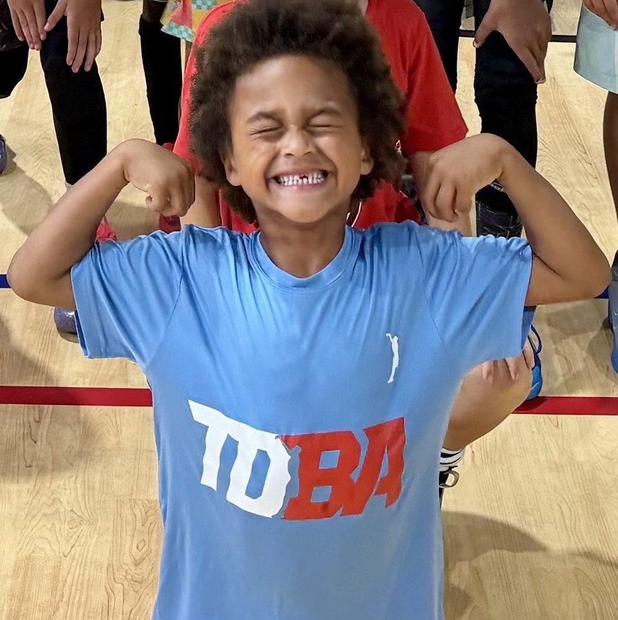 A young TDBA player flexing and grinning on the court